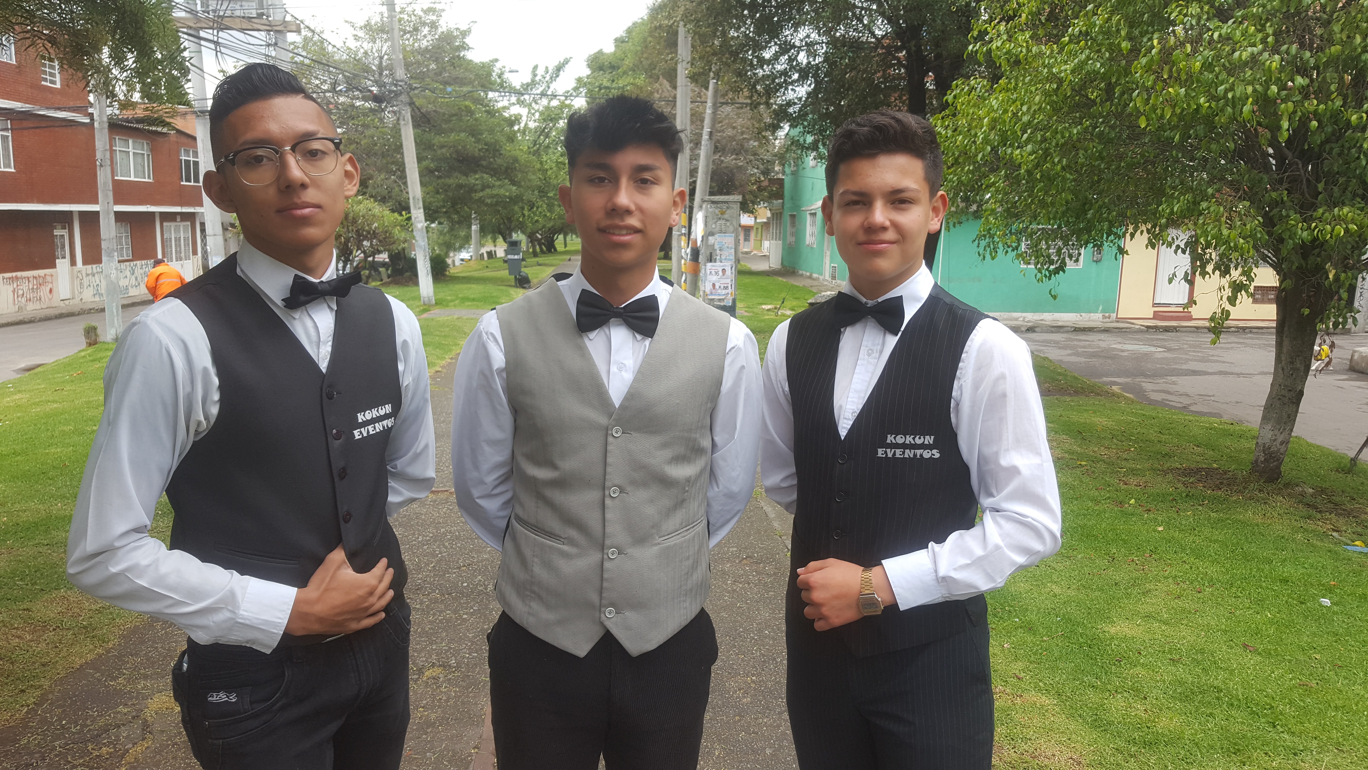 Meseros profesionales uniformados atendiendo elegantemente un evento corporativo con invitados interactuando en un ambiente sofisticado.